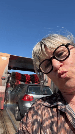 Woman takes selfie at active car wash in Chambœuf