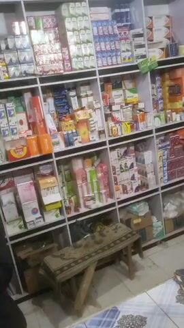 The video begins inside a pharmacy with shelves full of medicine. The camera is tilted up towards the shelves before quickly panning down and then abruptly cutting to a dark screen. The video then shows an outdoor shot of ground with dirt and small rocks. The camera remains focused on the ground.