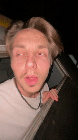 Train passenger smiles from window during nighttime journey through Montenegro