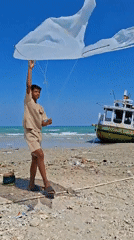 Kite flying and fishing boats on a Camplong beach morning