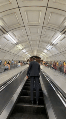 Man in suit uses moving walkway in London tunnel