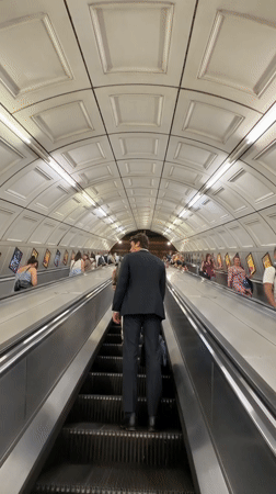 Man in suit uses moving walkway in London tunnel