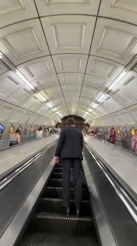 Man in suit uses moving walkway in London tunnel