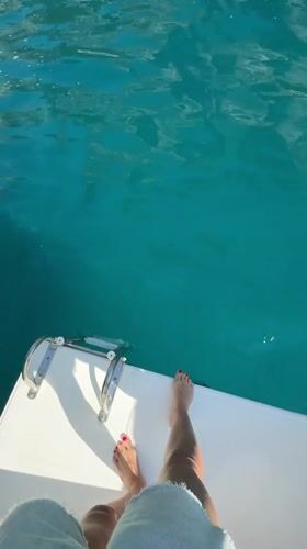 Tourist documents morning yacht cruise around Capri's Faraglioni rocks