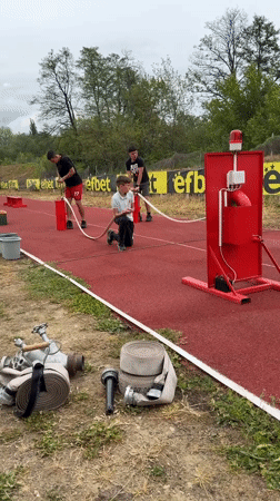 Boys operate water hoses on athletic track in Kazanlak
