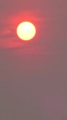 Sun glows red through a thick, hazy sky