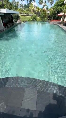 Resort guest documents early morning poolside relaxation in Ubud