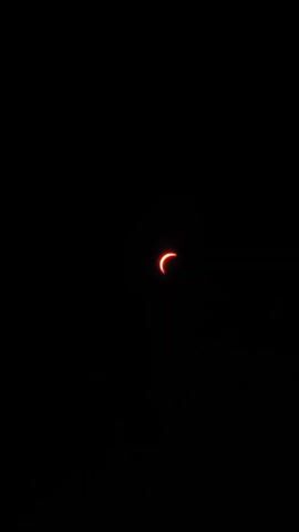 This is a video of a solar eclipse. The sun is partially obscured by the moon, creating a crescent shape. The sky is dark, indicating that it is either night or the eclipse is occurring during the day. The eclipse is viewed from Earth.
