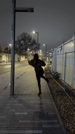 Woman skips playfully along Belgrade sidewalk at night