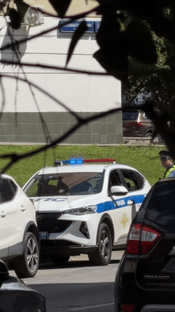 Police SUV parked roadside in Khimki, officer standing by
