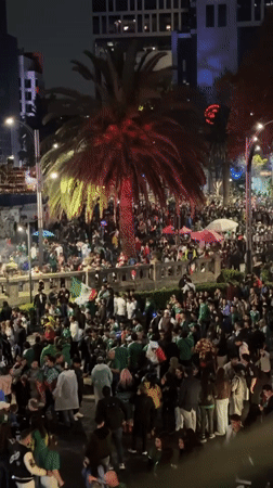 Mexico City crowds in green flood the plaza at night