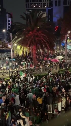 Mexico City crowds in green flood the plaza at night