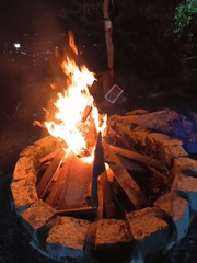 Nighttime bonfire burns in stone-lined pit
