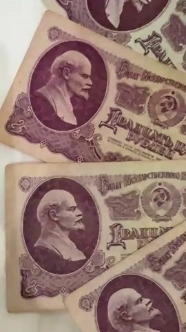 A close-up shot shows several Soviet rubles arranged in a circular pattern. The banknotes feature a profile portrait of Vladimir Lenin in the center, surrounded by intricate designs, including the Soviet emblem (hammer and sickle) and text. The lighting is soft, highlighting the textured paper of the currency. The background is a plain, light-colored surface.