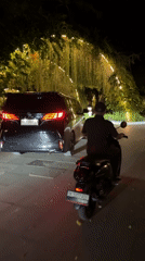 Man rides moped through lit garden archway in Kuta Selatan