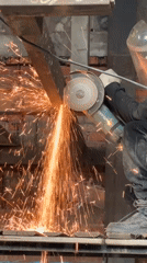 Worker cuts metal with angle grinder in industrial facility