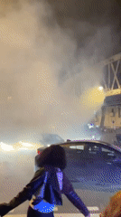 Large nighttime crowds gather in central Paris with flags
