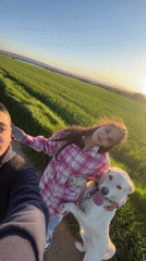 Couple walks golden retriever through Bulgarian countryside fields