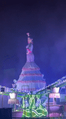 Costumed woman performs on illuminated parade float in Barcelona