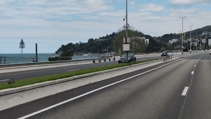 Car travels coastal highway in Sochi near ocean pier