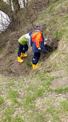 Children in yellow boots explore natural outdoor terrain