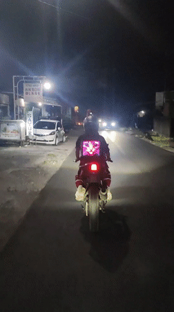 Motorcyclists travel roads near Ubud, one wearing glowing cat shirt