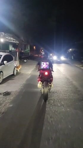 Motorcyclists travel roads near Ubud, one wearing glowing cat shirt