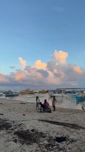 Children play on beach among fishing boats in General Luna