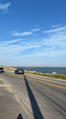 Vehicles travel oceanside road in sunny Provincetown