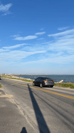 Vehicles travel oceanside road in sunny Provincetown