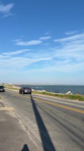 Vehicles travel oceanside road in sunny Provincetown