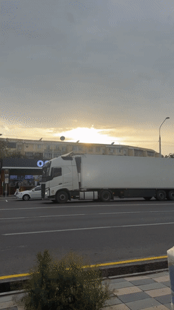 Commercial truck passes through Tashkent as birds circle overhead