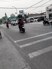 Busy Serang intersection with foot traffic, motorcycles, and a street food cart