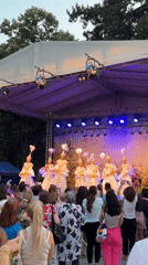 Costumed dancers perform under colored lights on a Shumen stage