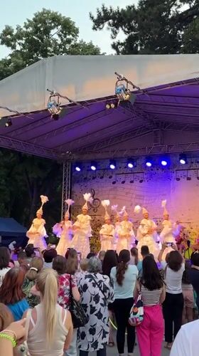 Costumed dancers perform under colored lights on a Shumen stage