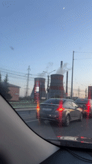 Evening traffic passes industrial cooling towers in Cheboksary