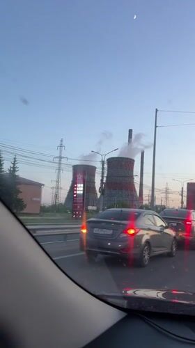 Evening traffic passes industrial cooling towers in Cheboksary