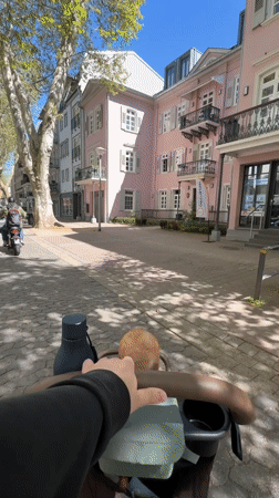 Parent pushes stroller through sunny Bad Kreuznach streets