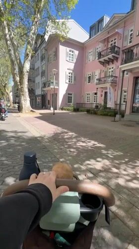 Parent pushes stroller through sunny Bad Kreuznach streets