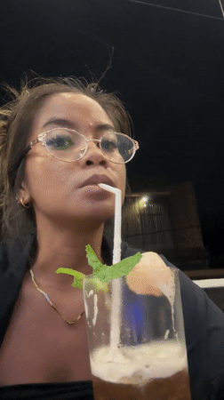 Woman enjoys garnished iced drink in Sukawati, Indonesia
