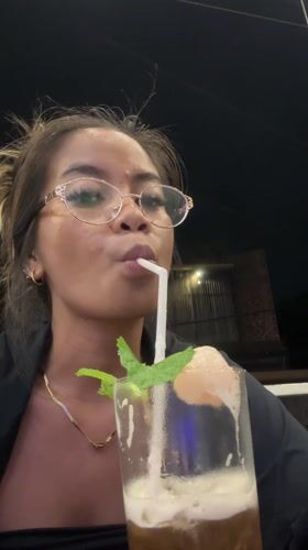 Woman enjoys garnished iced drink in Sukawati, Indonesia
