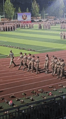 Mass uniformed formation on floodlit Chongqing sports field at night