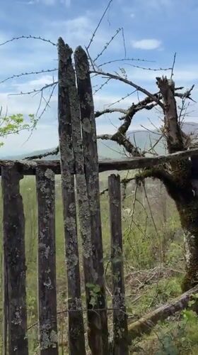 Rural landscape with weathered fence, cross documented in Vakhani