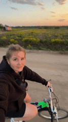 Woman cycles dirt road at sunset in rural Russia