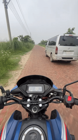 Motorcycle rider navigates brick road in Panchkhola, Bangladesh