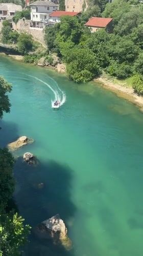 Boat travels Neretva River near historic Stari Most bridge