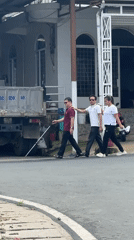 Three people walk together, one guided with white cane