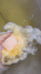 Person drops orange bath bomb into green water in Russia