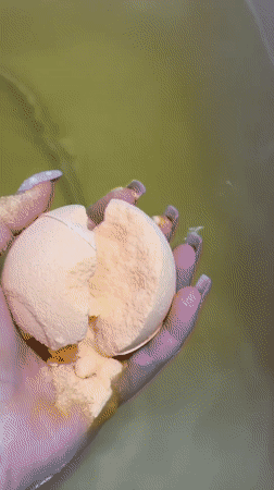 Person drops orange bath bomb into green water in Russia