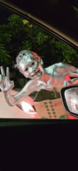 Silver-painted person gestures with box near car in Denpasar